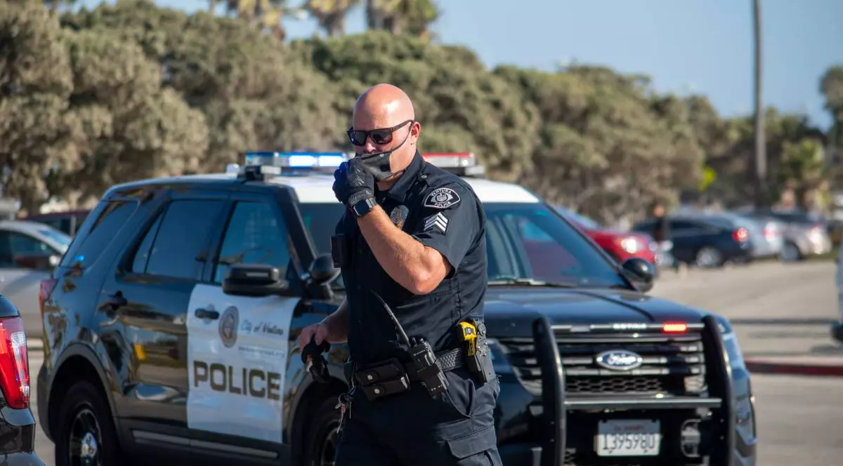 Un polițist din California, în uniformă, în timpul unei intervenții. Bărbatul stă în mașinii de Poliție