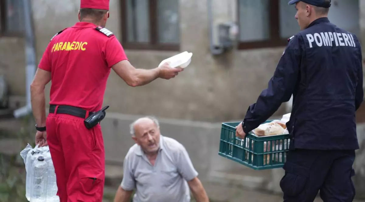 Pompierii din cadrul IGSU, în timp ce împart pâine și apă localnicilor din Broșteni, un bărbat trist primește de la aceștia două pachete și o sticlă de apă