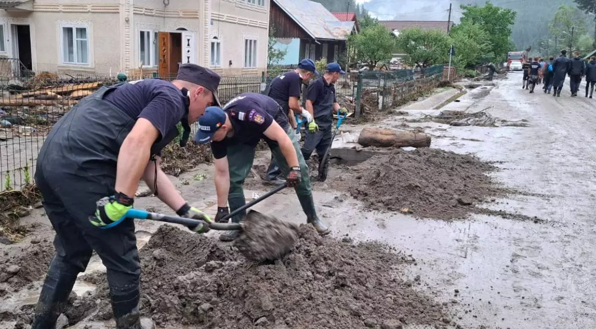 Pompierii militari în timp ce sapă cu lopețile șanțurile în localitatea Broșteni și încearcă să scoată noroiul din curțile oamenilor