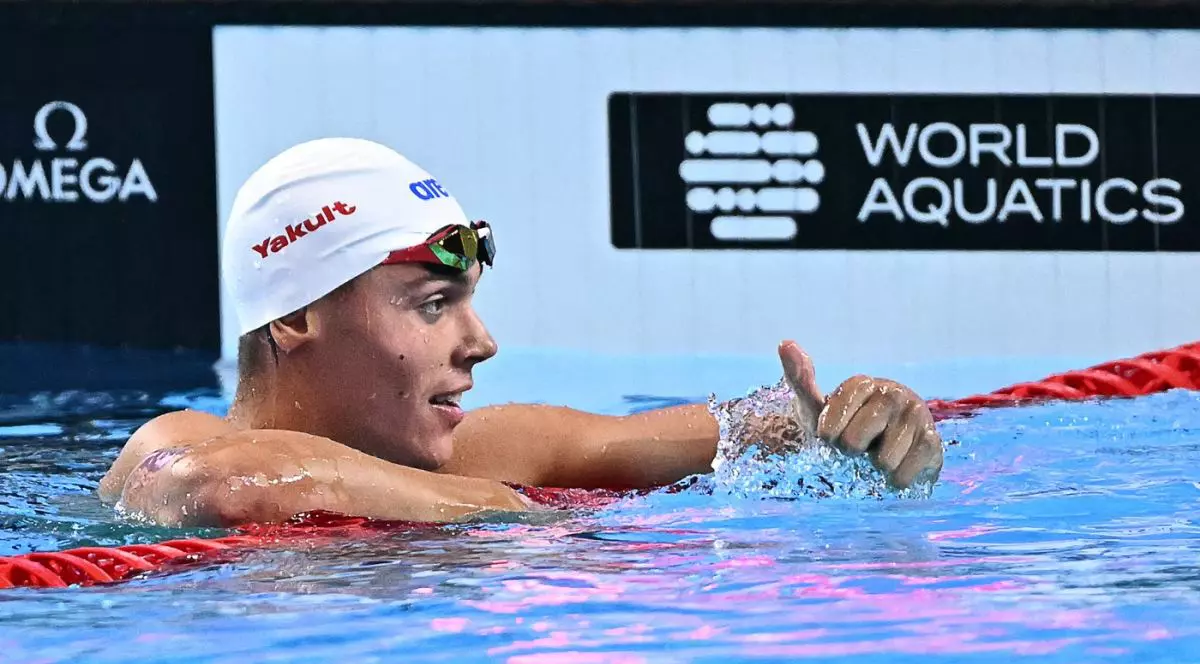 David Popovici, aflat în bazin și cu cască albă pe cap, ridică degetul mare în sus după ce a aflat timpul scos în semifinalele probei de 100 m liber de la Campionatul Mondial din Singapore, 30 iulie 2025
