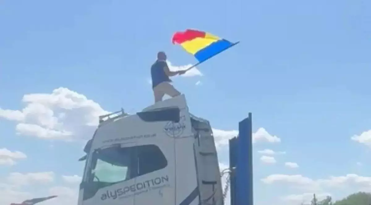 Șoferul de TIR de 33 de ani, urcat pe cabina autotrenului care bloca intrarea în București, în timp ce flutură drapelul României