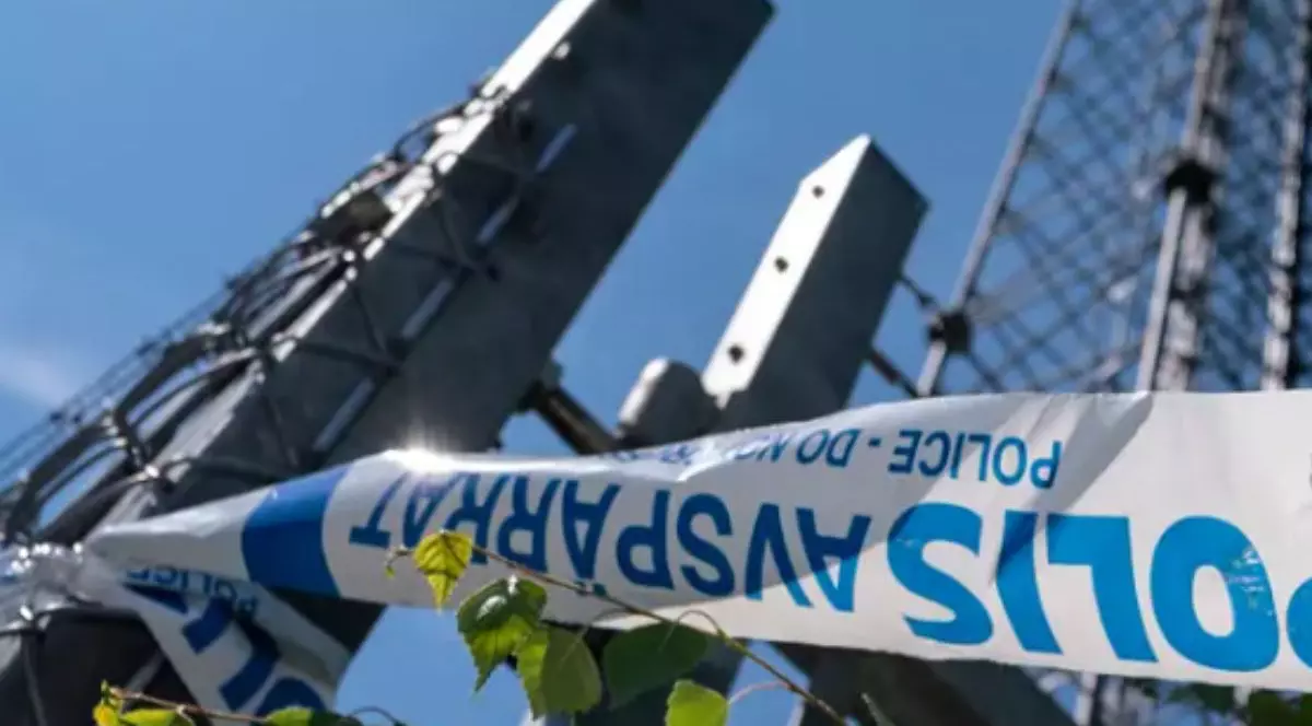 Imagine de jos cu niște turnuri de telecomunicații sub un cer albastru, in prim plan o bandă alb cu albastru cu scris pe ea, conceptul de sabotaj în telecomunicații