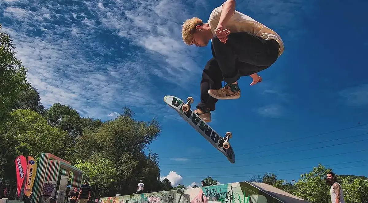 Un tanar face o saritură cu placa de skateboard