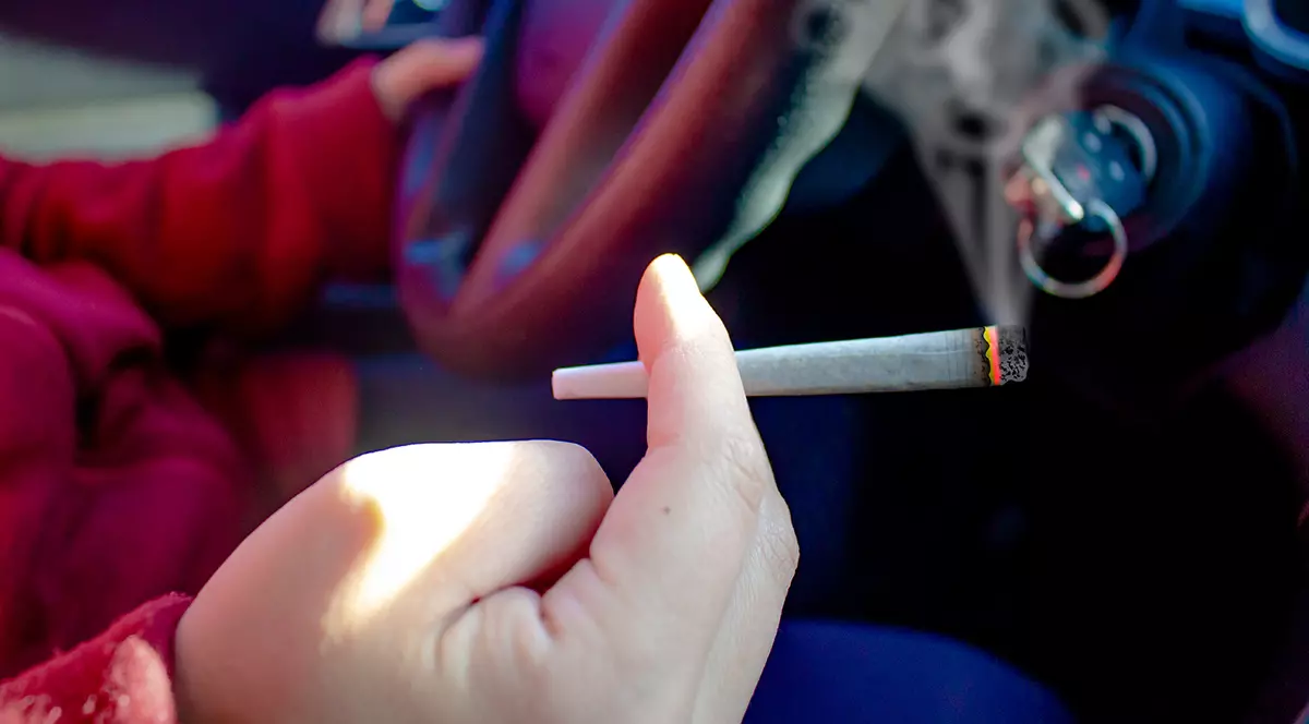 O persoană cu un joint de canabis fumând și conducând. Concept: conducere sub influența alcoolului, conducere sub influența alcoolului sau a drogurilor