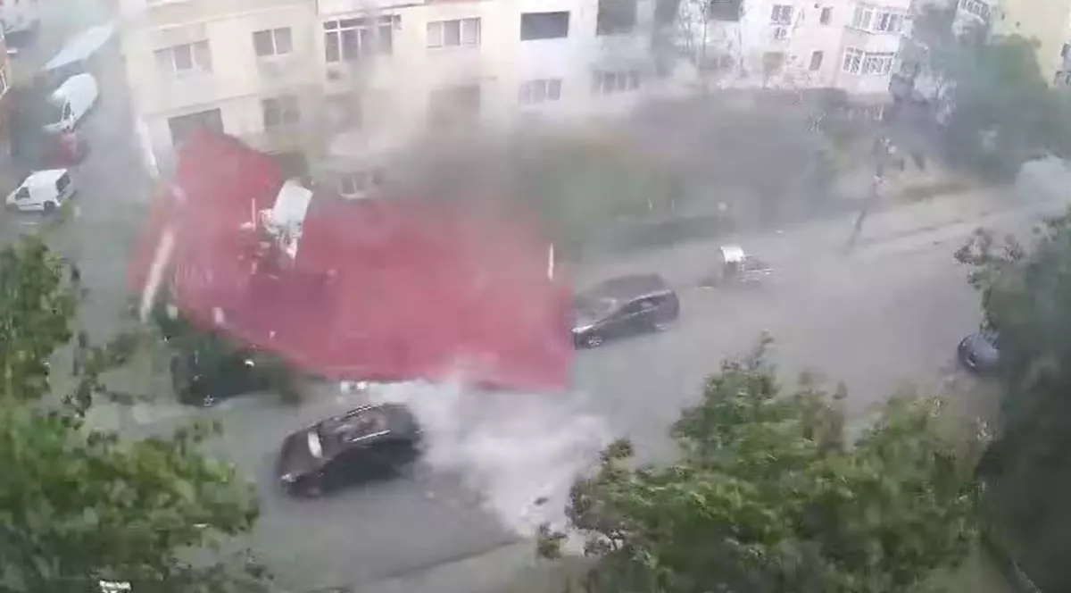 Momentul în care un șofer trece cu mașina pe stradă chiar în timp ce acoperișul unui bloc este aruncat la pământ