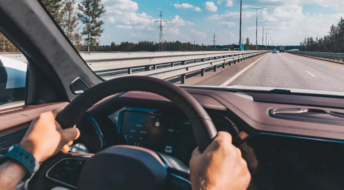 Un șofer care conduce o mașină pe autostradă