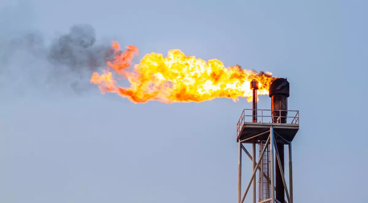 Sonda unei instalații de exploatare a gazelor naturale, care arde cu flacără deschisă, cu cerul albastru pe fundal