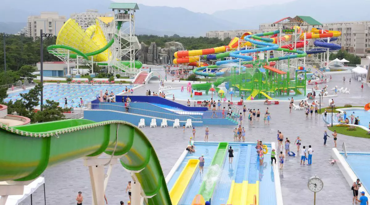 Stațiunea Wonsan Kalma din Coreea de Nord, in imagine se vad tobogane cu apă, puscine, turisti care se plimba sau se distrează, in fundal se observa muntii