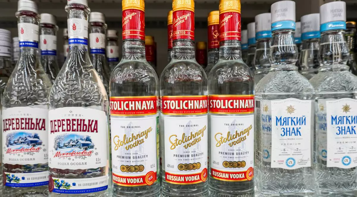 Zeci de sticle de votcă rusească stau pe rafturile unui magazin la vânzare
