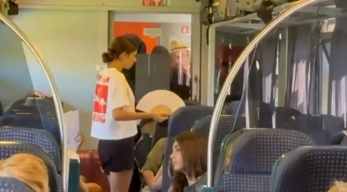 În imagine se vede un vagon de tren aglomerat, unde pasagerii se răcoresc cu evantaie pe caniculă, în lipsa aerului condiționat.