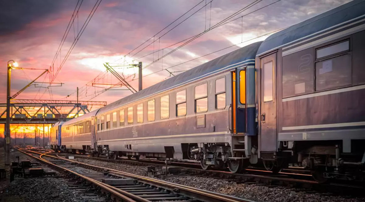 Un tren CFR pe șine în timp ce ajunge în gară la asfințit