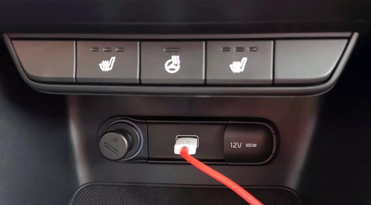 Bordul negru al unei mașini, cu un cablu roșu care este conectat la o priză USB