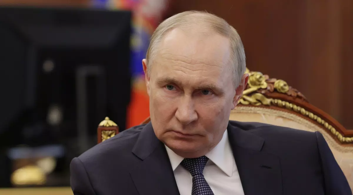 Vladimir Putin surprins în timp ce se încruntă. Liderul de la Kremlin stă pe scaun și poartă un sacou negru, o cămașă albă și o cravată cu buline albe