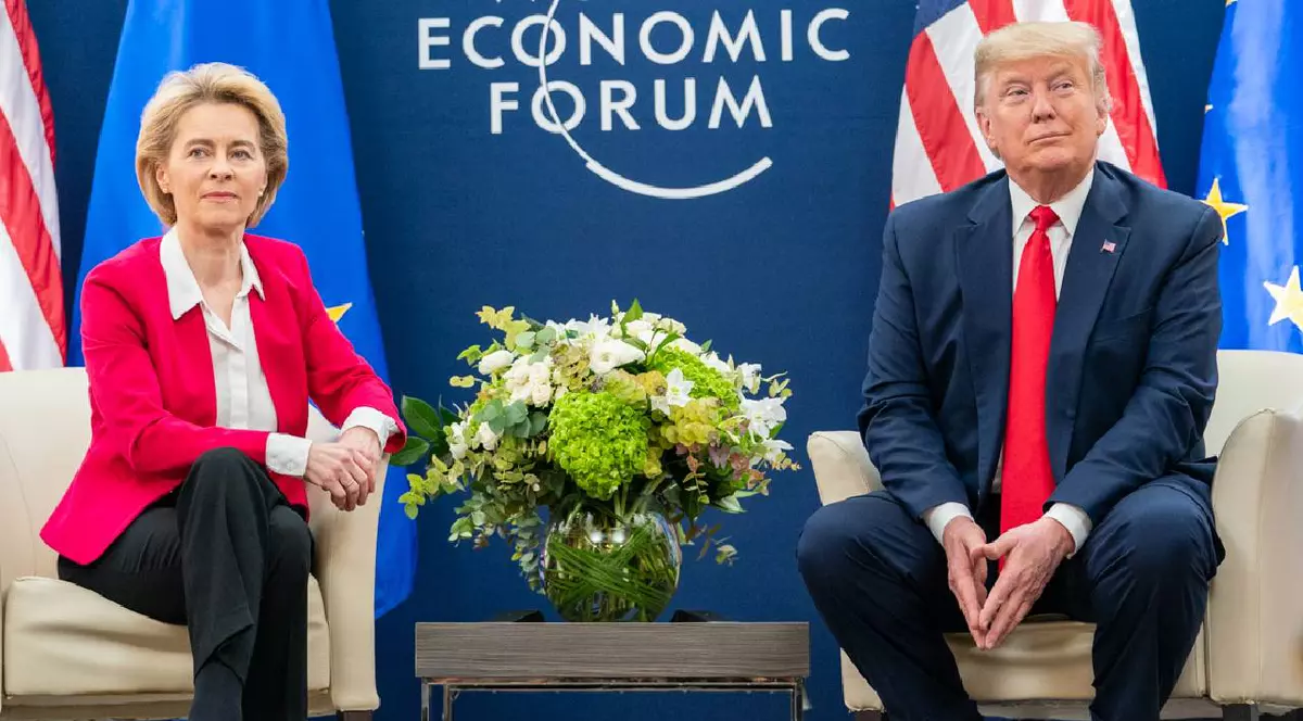 Ursula vonder leyen (stânga) și Donald Trump (dreapta) la un eveniment economic, între ei stă o vază cu flori și amândoi privesc obiectivul foto spre care zâmbesc