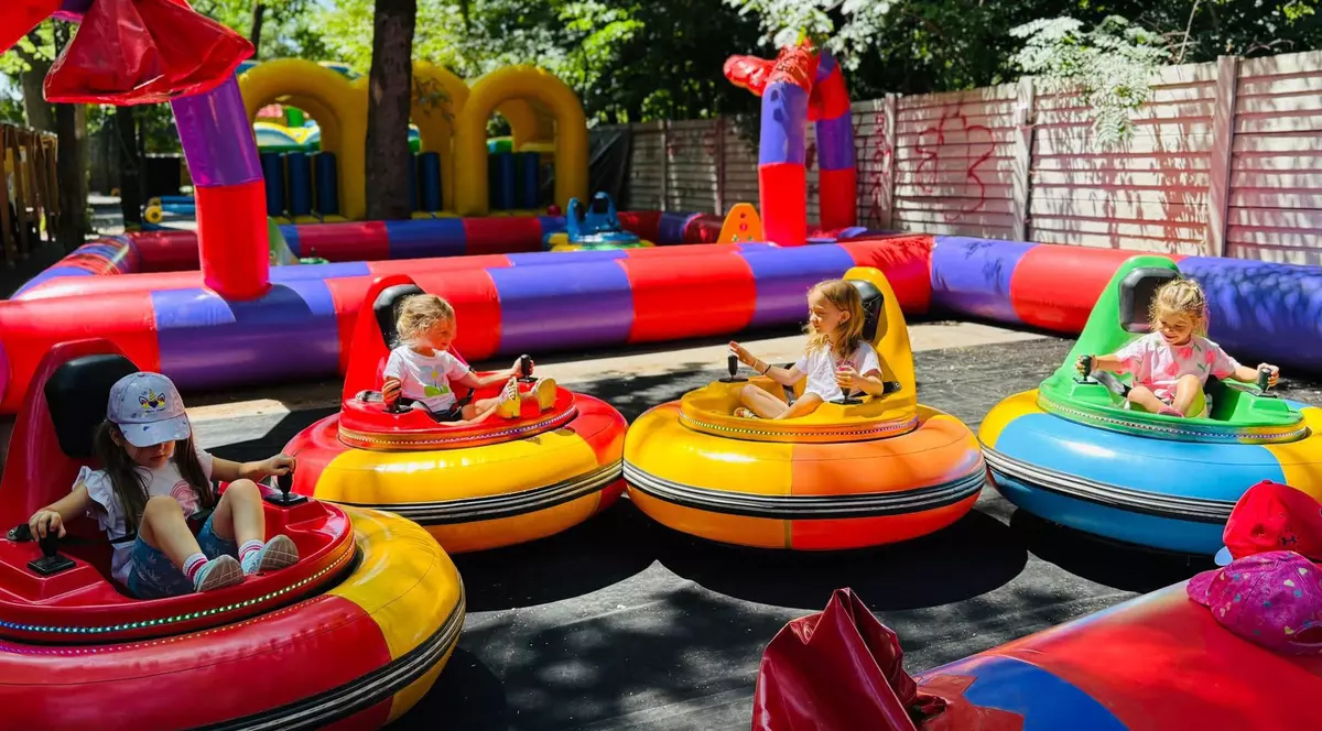 mai multi copii se joaca in niste gonflabile multicolorate
