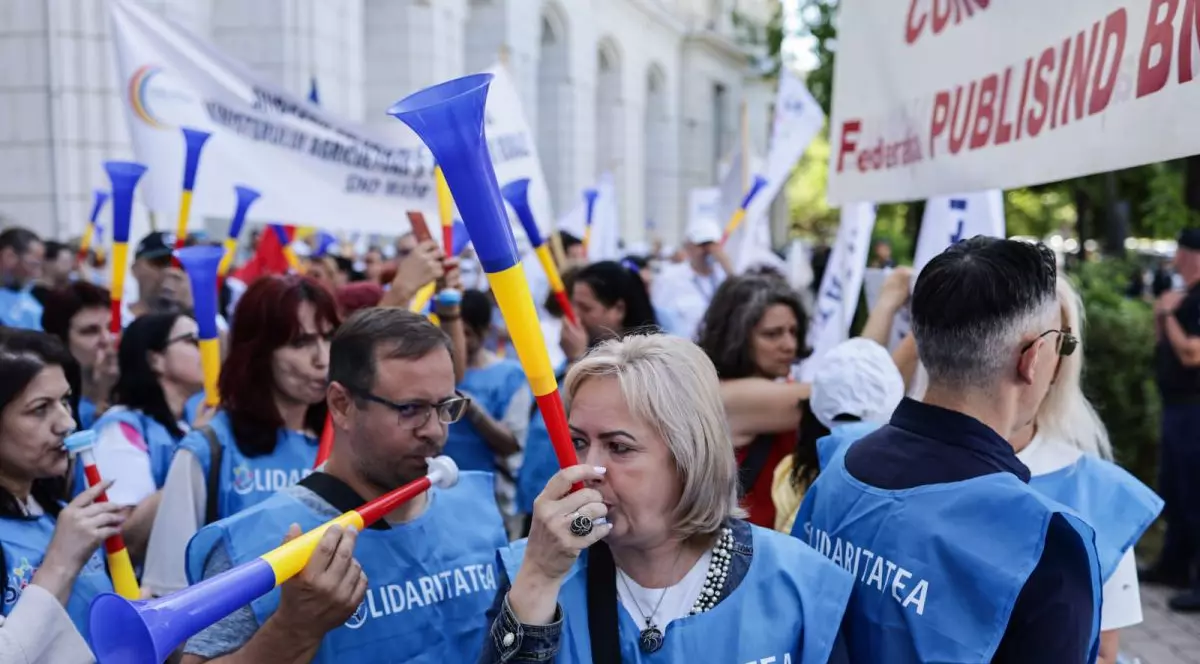 Protestatari îmbrăcați cu veste bleu suflă în vuvuzele în fața ministerului de finanțe din București, 10 iulie 2025