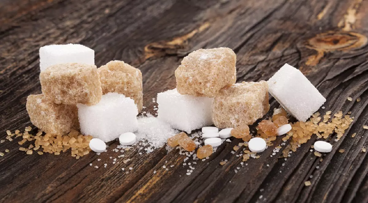 Diferite tipuri de zahăr - brun, alb, cristale, trestie și îndulcitori artificiali pe o masă de lemn