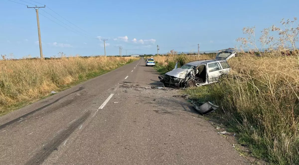 In imagine un drum prin camp, in dreapta se vede o mașină gri distrusa in urma unui accident, o alta masina se poate observa in depărtare, Buzau, august 2025