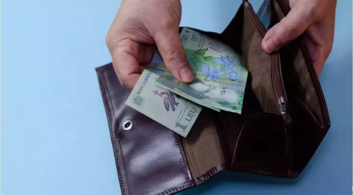 O femeie care scoate bancnote de un leu din portofel
