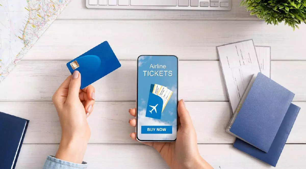 Femeie care își rezervă bilete de avion online, folosind un card bancar și un telefon mobil.