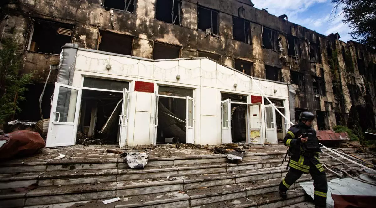 O clădirea din Ucraina bombardată în timpul războiului, pompierii fug cu un furtun de apă