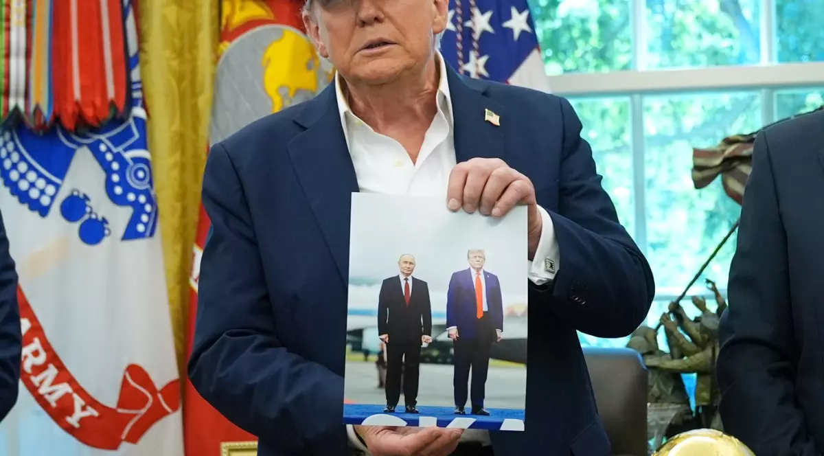 Președintele Donald Trump ține o fotografie cu el și președintele rus Vladimir Putin în timpul unei declarații în Biroul Oval al Casei Albe, vineri, 22 august 2025, la Washington.