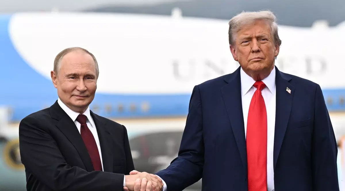 Vladimir Putin (stânga) și Donald Trump (dreapta) surprinși în timp ce-și strâng mâinile vineri, 15 august 2025, în Alaska