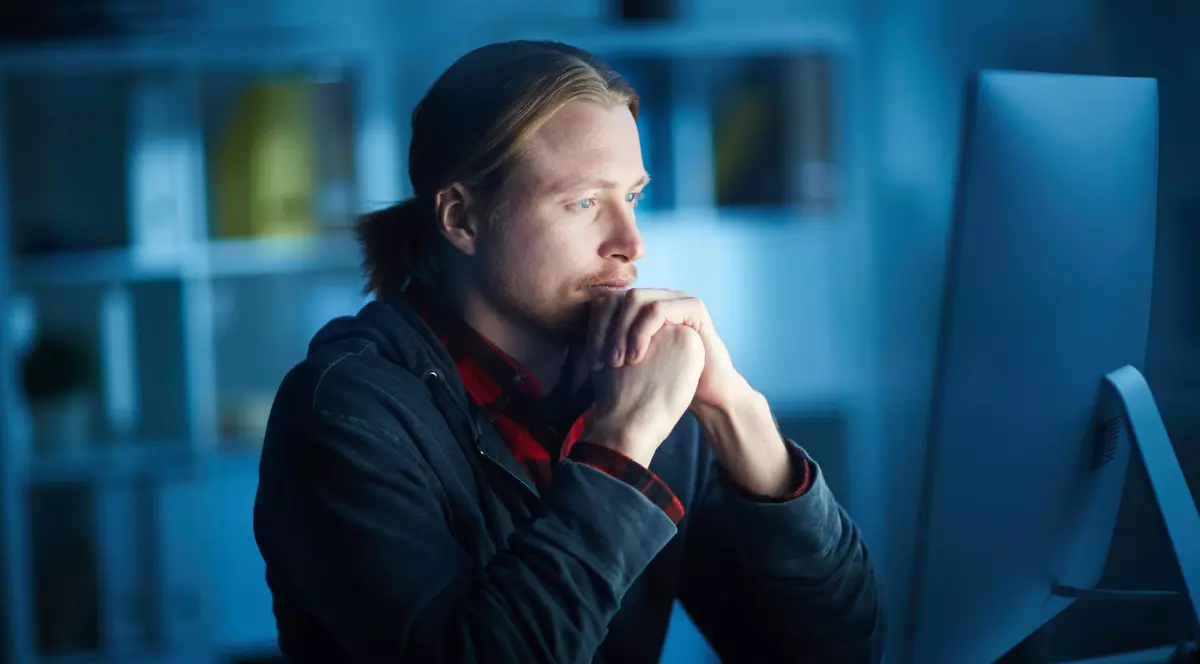 SOLO - Serious man looking at a computer screen, in a dark office