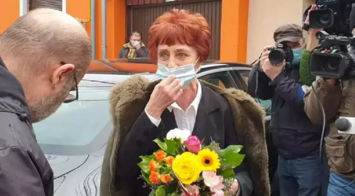 Medicul pneumolog Flavia Groșan, cu o mască pe gură, un buchet de flori în mână. Lângă ea se află fotografi și jurnaliști
