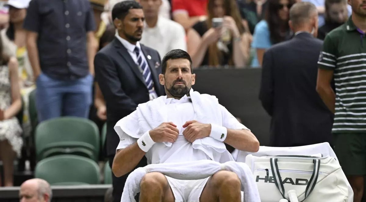 Novak Djokovik stă pe scaun, la marginea terenului, având pe spate un prosop alb și un alt prosop pe picioare, iulie 2025