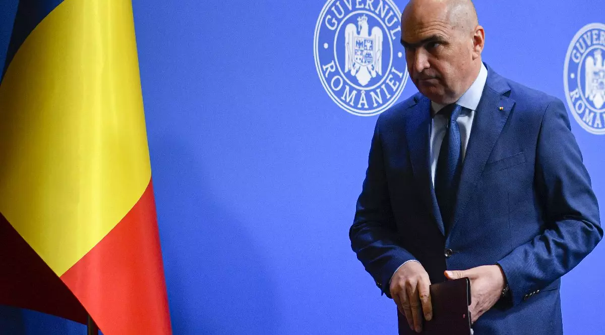 Premierul Ilie Bolojan, îmbrăcat în costum albadstru închis, pleaca la finalul unei conferinte de presa cu privire la reforma pensiilor in sitemul de Jutitie, marti, 29 iulie 2025, in Bucuresti. In fundal, în stânga se vede și steagul României.