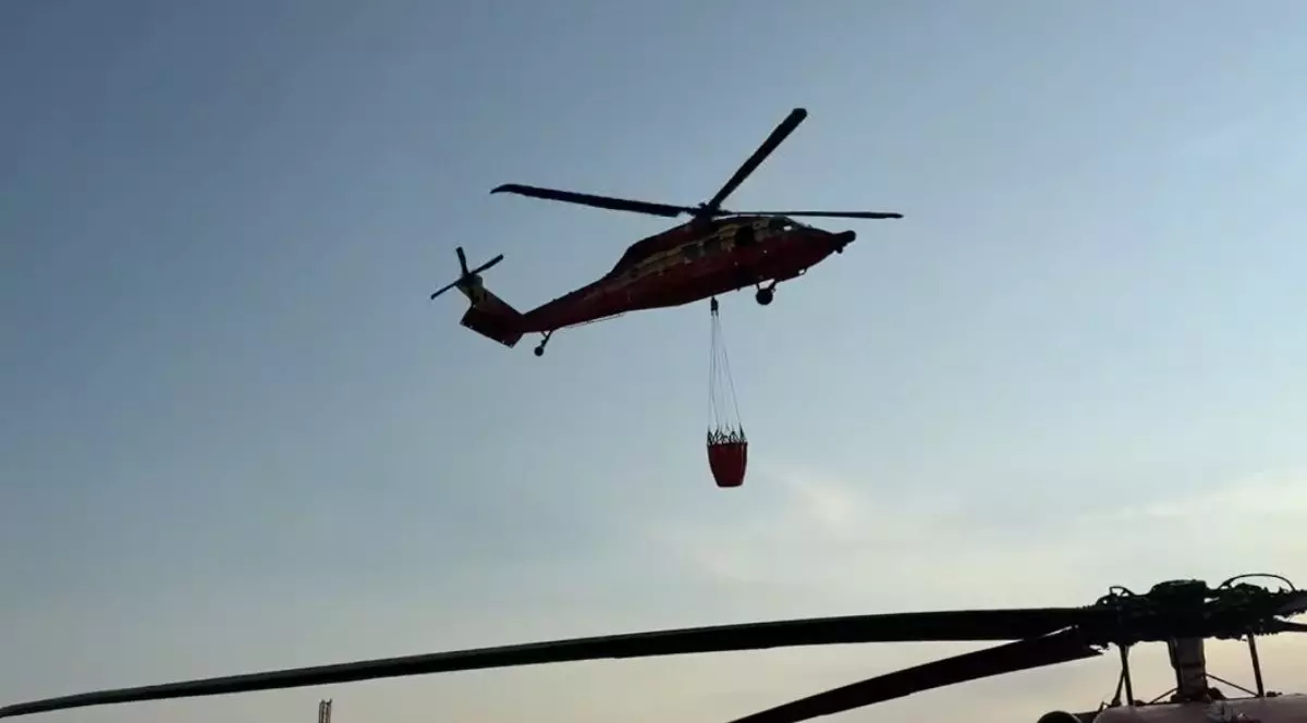 elicopter ISU Tulcea model Black Hawk, vopsit în roșu cu dungi galbene, care cară încărcături cu apă peste incendiul de vegetație din Chilia Veche, Tulcea, 7 august 2025