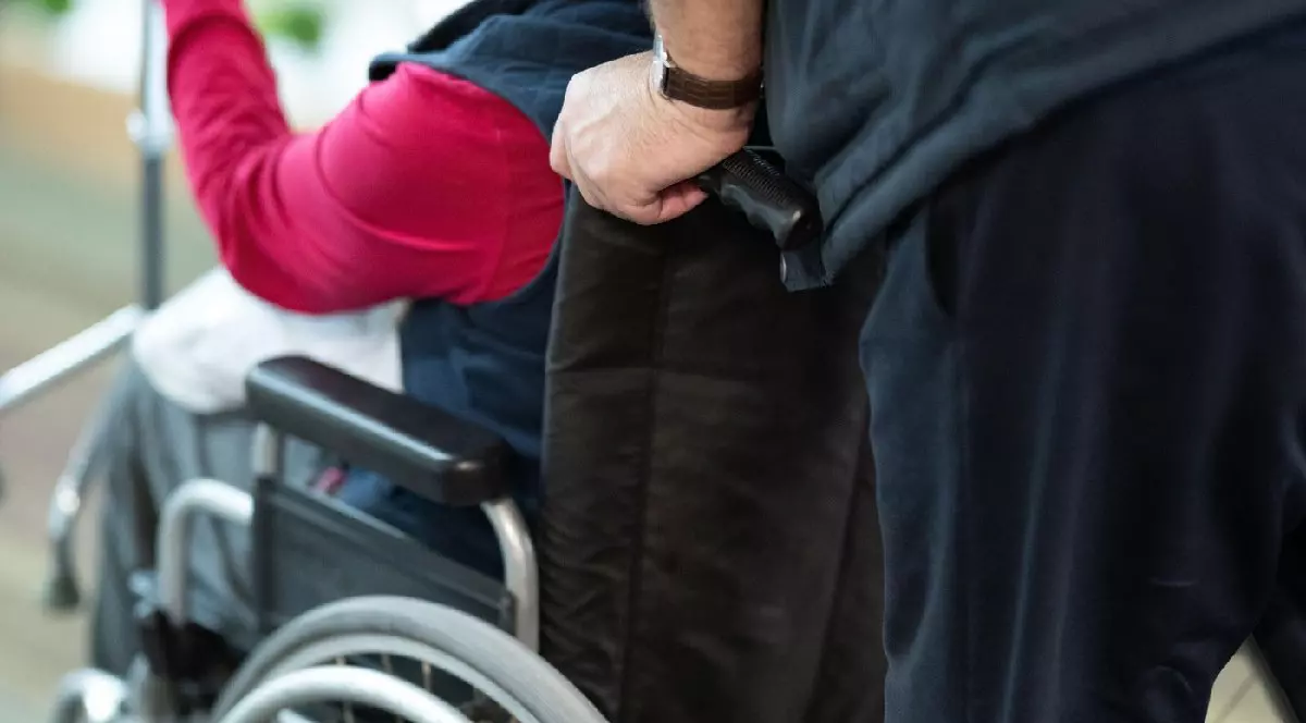 Vedere parțială a unei persoane care ajută pe cineva într-un scaun cu rotile