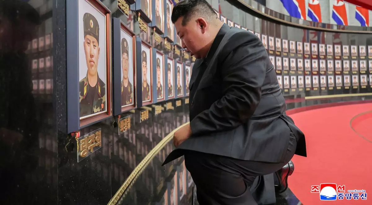 Kim Jong-un, îmbrăcat într-un costum negru, stă în genunchi în fața fotografiilor cu soldații morți în Kursk în timpul unei vizite la zidul memorial în cadrul unei ceremonii de decernare a distincțiilor de stat comandantului și combatanților Forțelor Operaționale de peste hotare ale Armatei Populare Coreene, care au participat la operațiuni militare în regiunea Kursk din vestul Rusiei, la sediul Comitetului Central al Partidului Muncitorilor din Coreea (WPK) din Phenian, 22 august 2025