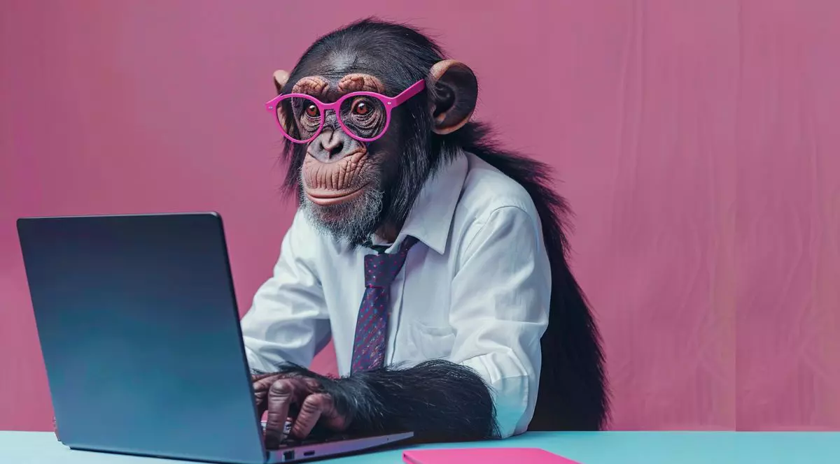 o maimuță îmbrăcată într-o cămașă albă și o cravată mov, purtând ochelari rotunzi roz, lucrând pe un laptop. biroul pe care se află laptopul este bleu iar fundalul este roz pastel