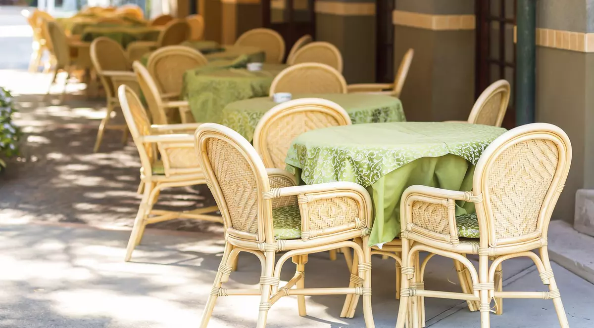 Imagine cu mai multe mese și scaune goale pe o terasă a unui restaurant.