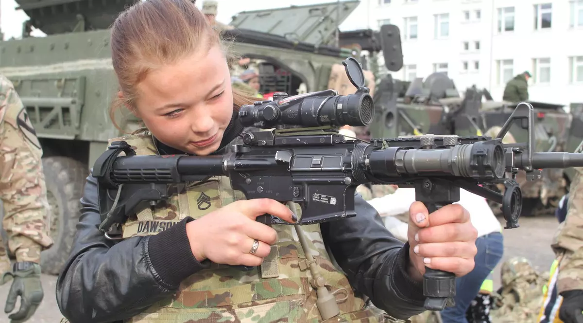 O elevă din Lituania examinează o armă de asalt americană la o expoziție, mai 2023