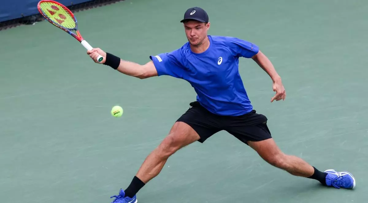 Kamil Majchrzak, cu șapcă neagră pe cap și îmbrăcat cu un tricou albastr, returnează o minge în timpul unui joc la US Open, august 2025