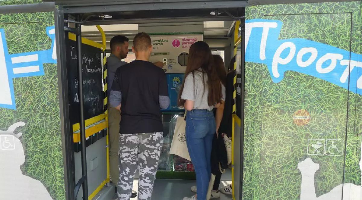Mai mulți oameni folosesc un aparat de reciclare, în Grecia