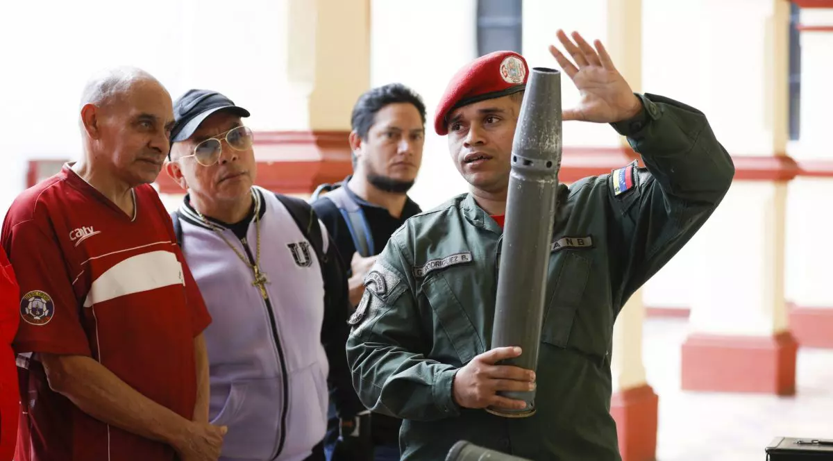 Un militar din Venezuela ține în mână o rachetă, în timp ce mai mulți voluntari se uită la el.