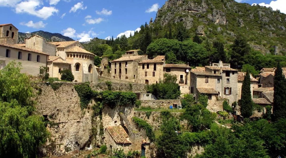 Căsuțe ascunse printre vegetație pe o colină din satul Saint-Guilhem-le-Désert