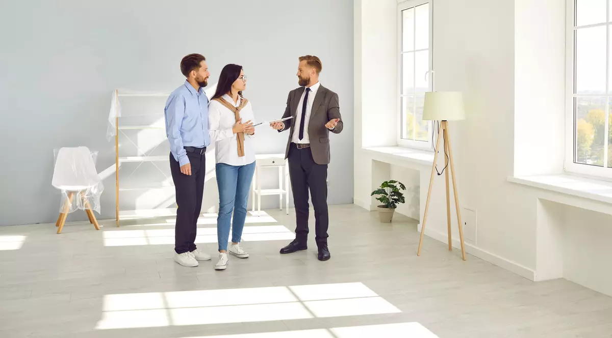 Cuplu, stau de vorba cu un agent imobiliar intr-un living spatios, luminos