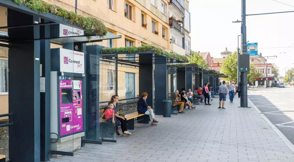 statie de autobuz din cluj, cu oameni care stau pe banci si asteapta autobuzul