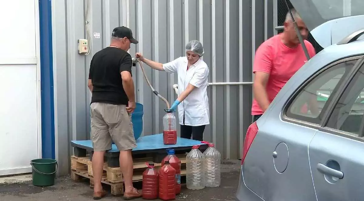 O persoană achiziționează suc de roșii ,cu bidonul, direct de la poarta fabricii