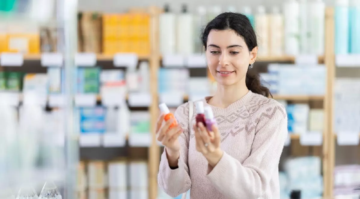 O tânără cumpărătoare alege lac de unghii într-o farmacie