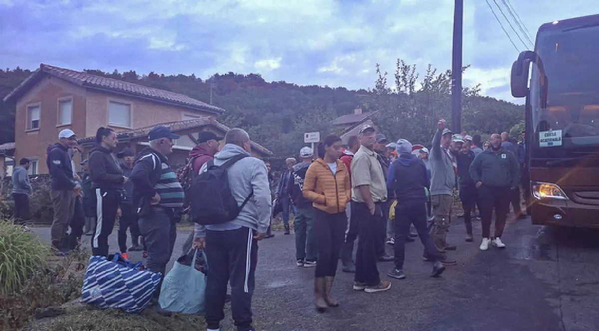 Mai multe persoane cară bagaje și așteaptă în fața unui autobuz