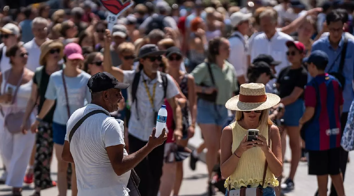 Turiștii vizitează Sagrada Familia protejându-se cu sticle de apă, evantaie, pălării și ventilatoare portabile în timpul unei valuri de căldură în Barcelona, Spania, pe 15 august 2025.