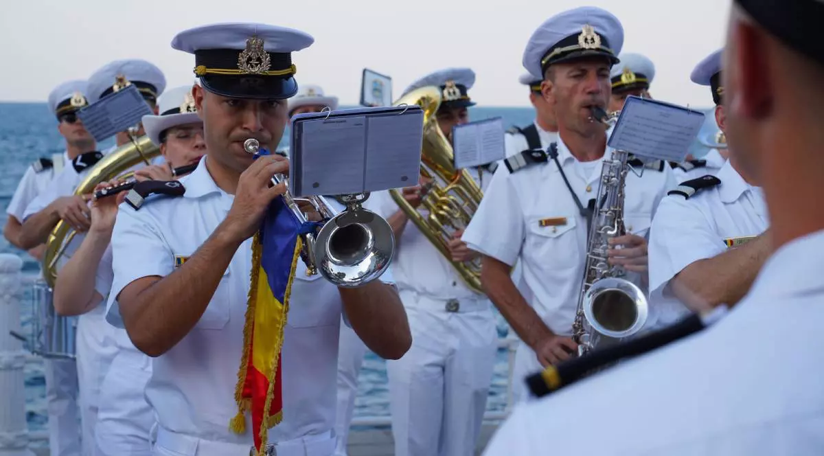 Mai mulți ofițeri ai Forțelor Navale Române în timp ce cântă la trompete în Portul Tomis de Ziua Marineri, aceștia sunt îmbrăcați în uniforme albe
