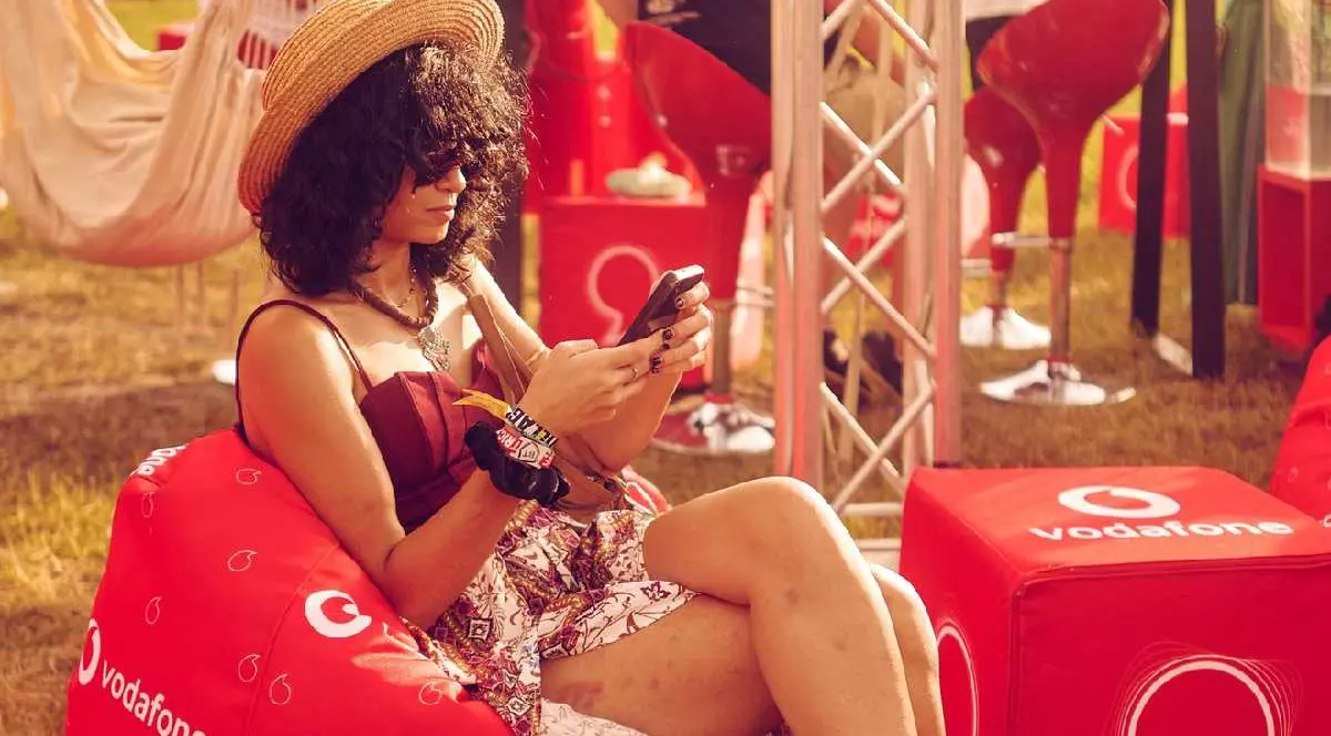 O femeie ține un telefon în mână și stă pe un fotoliu gonflabil pe care scrie Vodafone