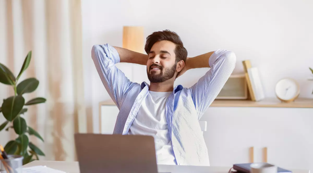 Angajat obosit de atâta stat pe scaun la birou, în fața laptopului